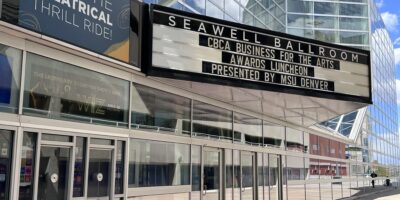 Marquee outside Seawell Ballroom advertises "CBCA Business for the Arts Awards Luncheon presented by MSU Denver." Modern glass building and a sign reading "Join the Theatrical Thrill Ride!" are also visible.